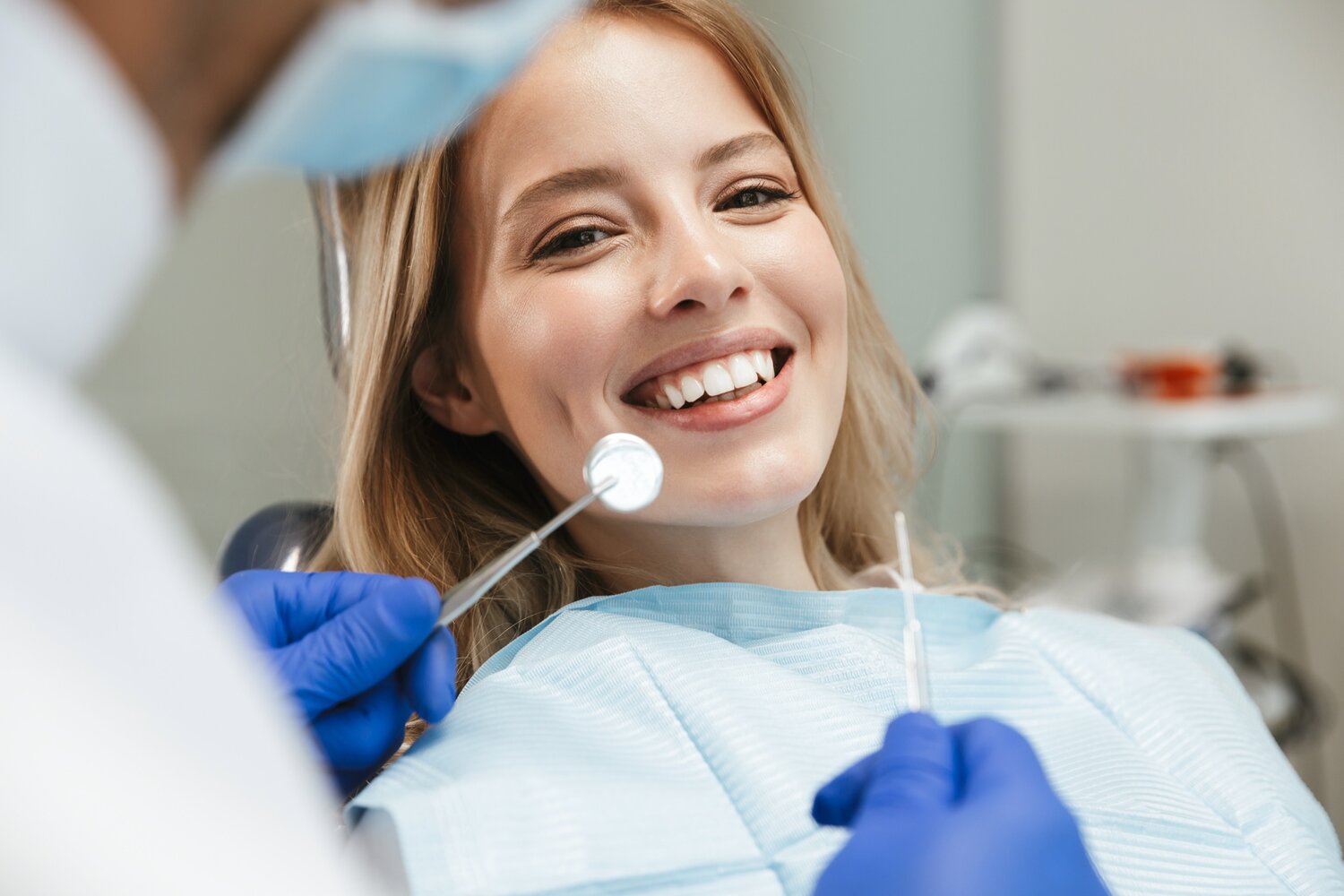 Image of satisfied woman sitting in dental chair while professional doctor fixing her teeth